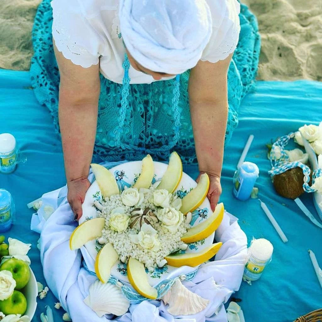 Oferenda espiritual com flores, frutas e velas sobre tecido azul